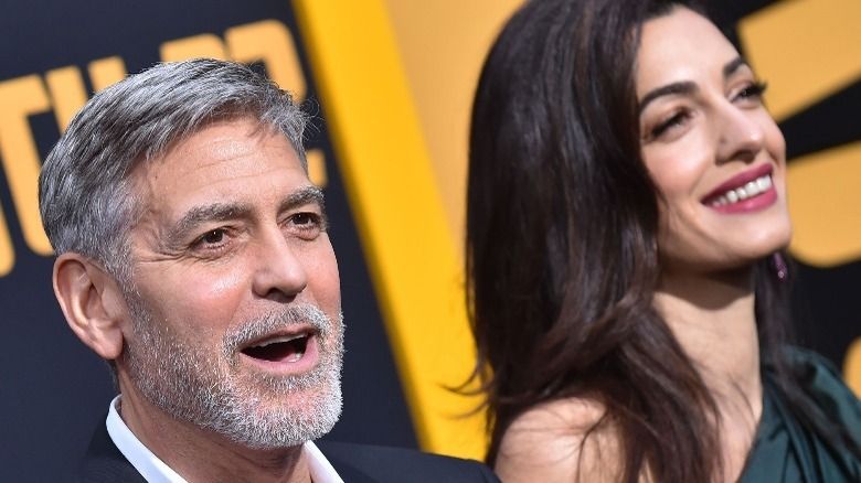George Clooney spricht und Amal Clooney lächelt