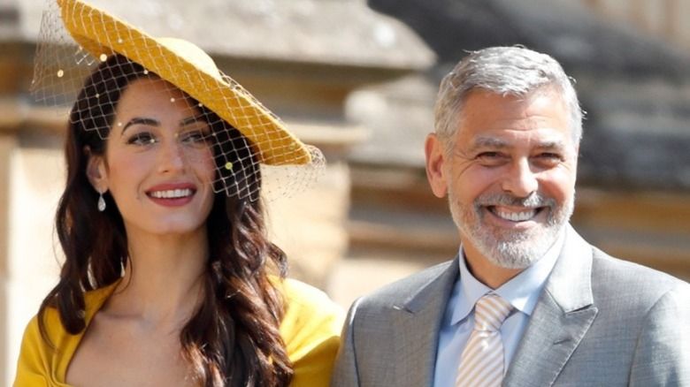 Amal Clooney mit gelbem Hut und George Clooney lächelnd