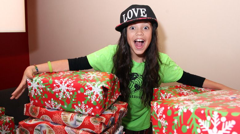 Eine junge Jenna Ortega mit großen Weihnachtsgeschenken