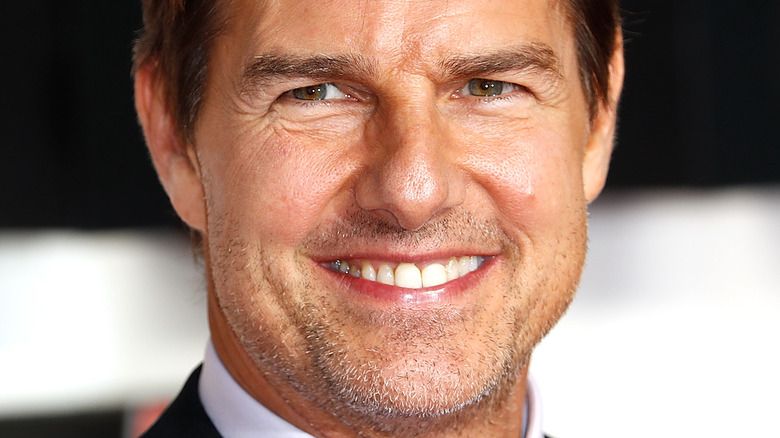 Tom Cruise lächelt mit Bartstoppeln im Gesicht