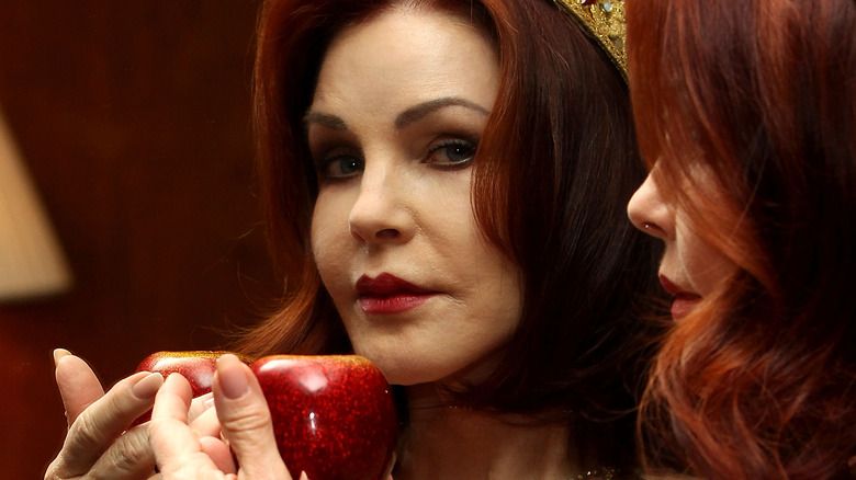 Priscilla Presley hält einen Apfel