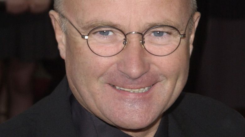 Phil Collins posiert mit runder Brille